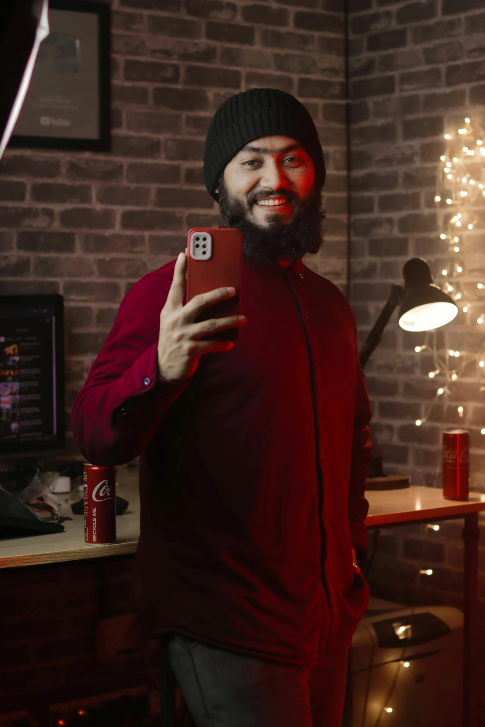 a man standing in front of a red phone with a brick wall