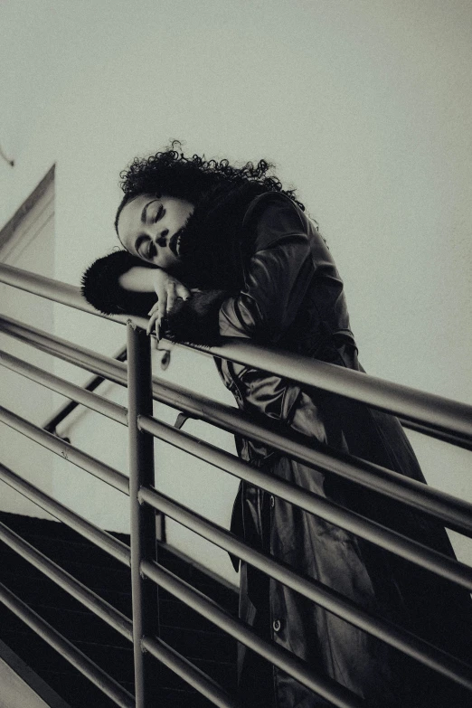 a woman sitting on the handrail of a metal fence