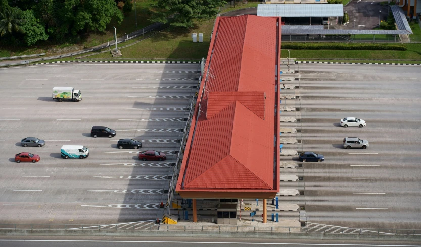 a parking lot with parked cars, with two buildings and one building with red roof