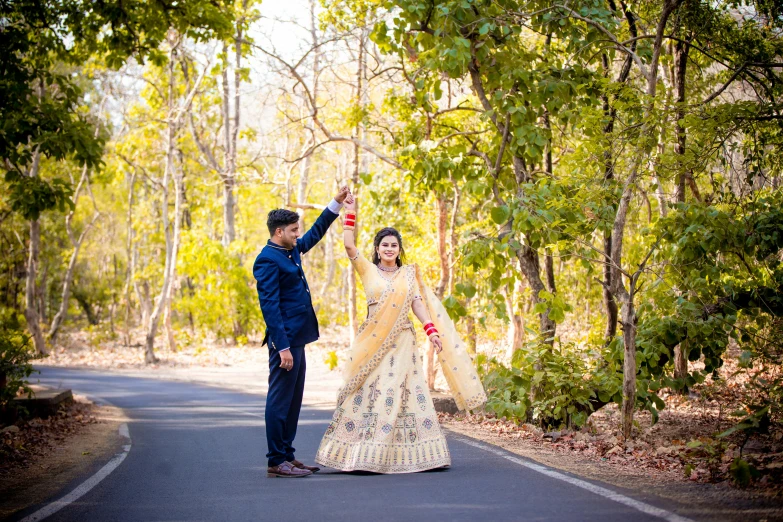 a bride and groom walking down a country road with trees around them