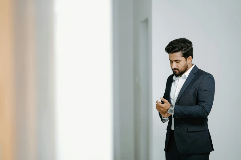 a young man in suit checks his cell phone