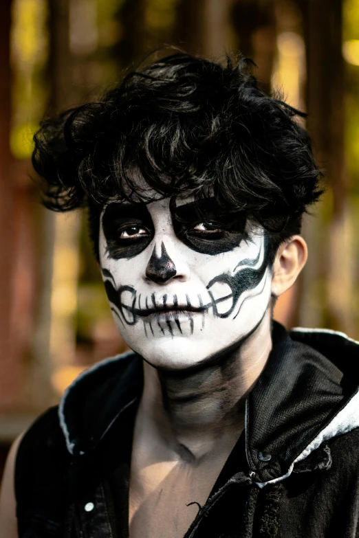 a man with black hair and white skull makeup on
