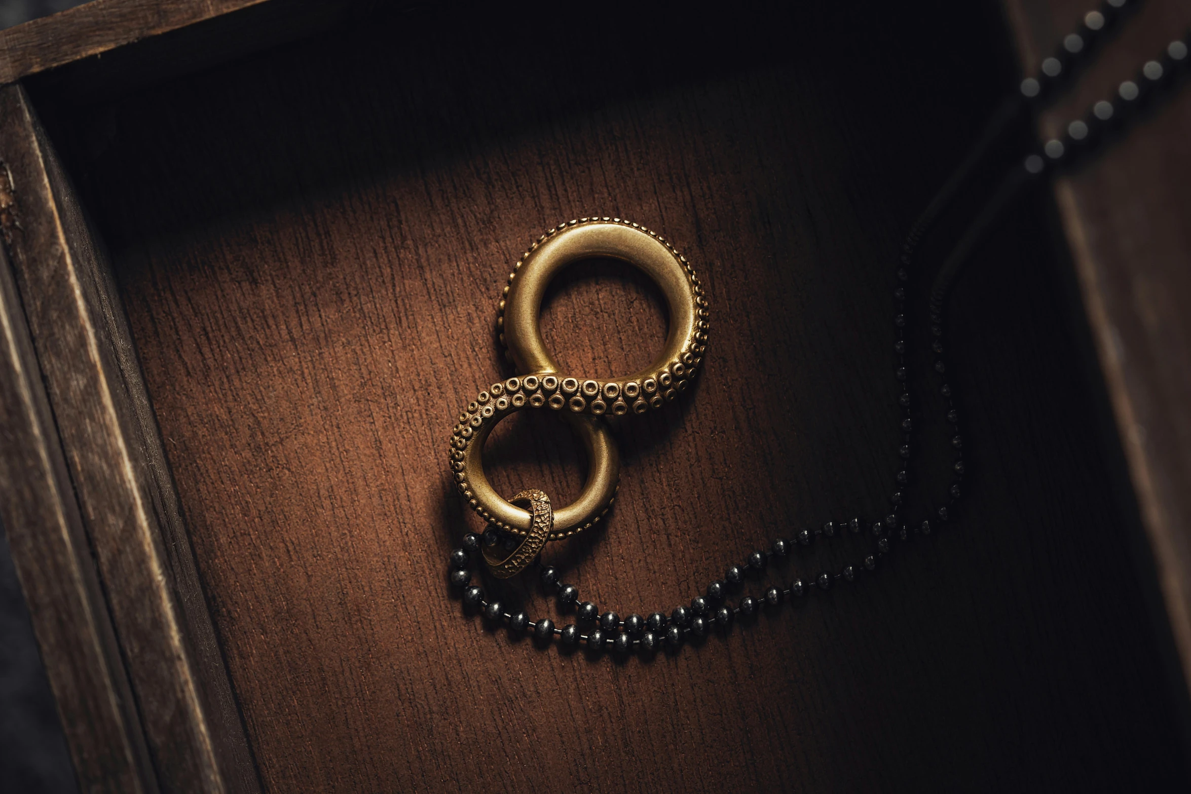 a po of two gold rings on a black bead necklace