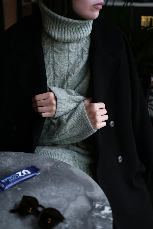 a woman wearing a jacket is holding her hands on the shoulder of her coat