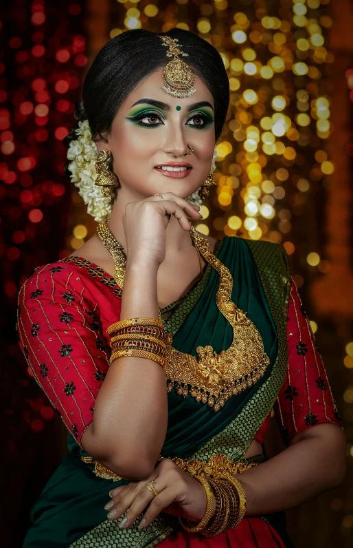 an indian woman with green makeup wearing a necklace and a saree