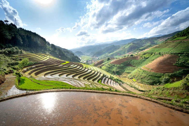 a large pond surrounded by green mountains with a sky background