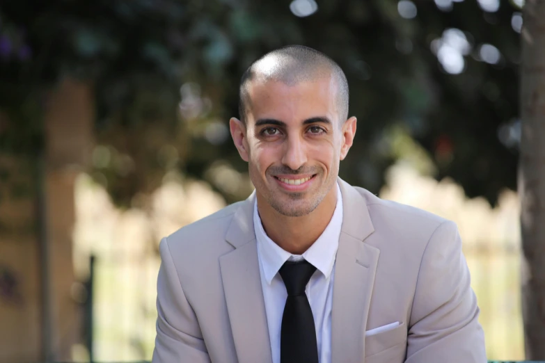 a smiling man in a white suit and black tie