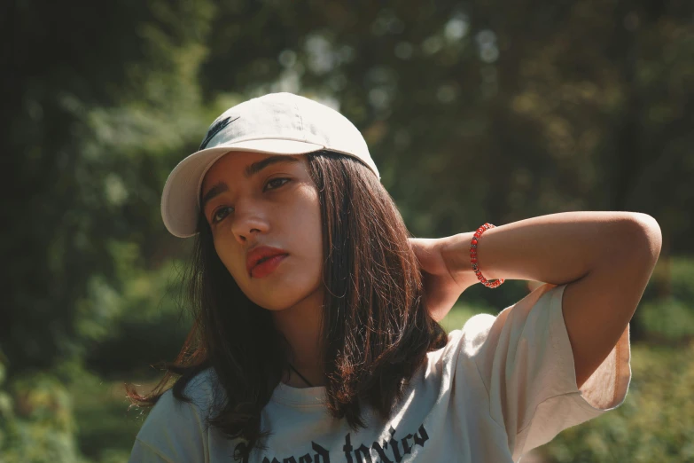 a young woman wearing a hat is posed with her hand on the side of her head