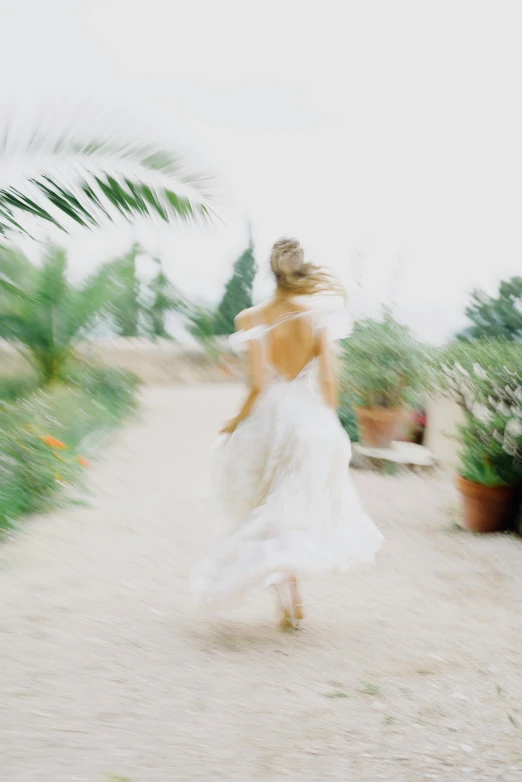 a woman in white dress running down a trail