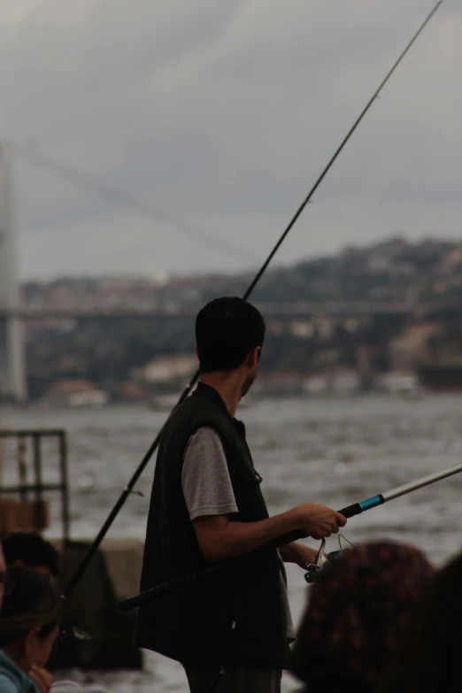 the man is fishing in the river in a city