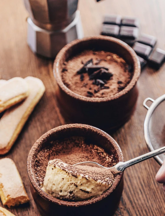 a hand is spooning into a bowl filled with batter