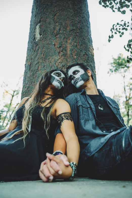 two people sitting next to each other near a tree