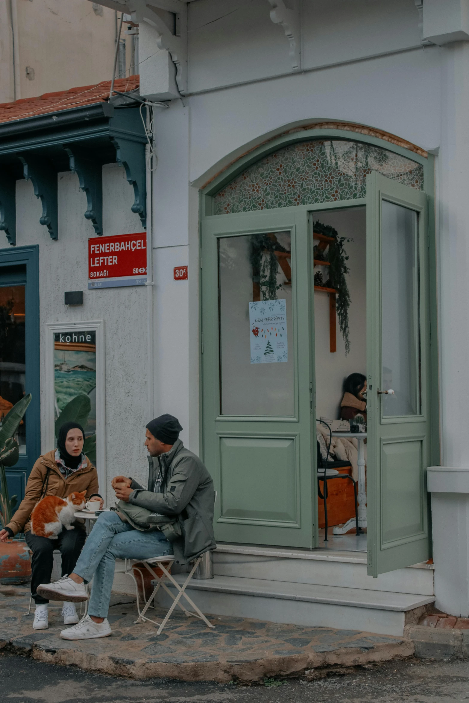 two people sitting on chairs outside of a white building