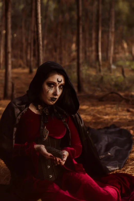 woman in red dress with hood sitting on ground