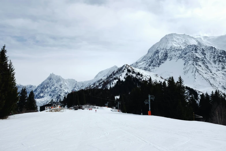 an empty ski slope with snow and mountains in the background