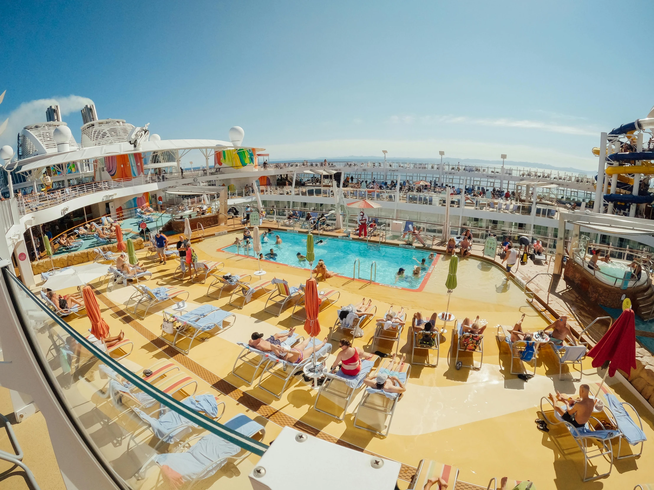 people sit at the edge of a swimming pool on a cruise ship