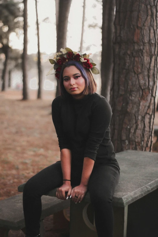 young woman sitting on bench outdoors wearing a floral crown