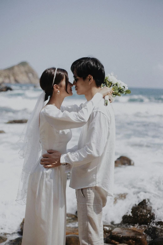 two people wearing white standing on the beach