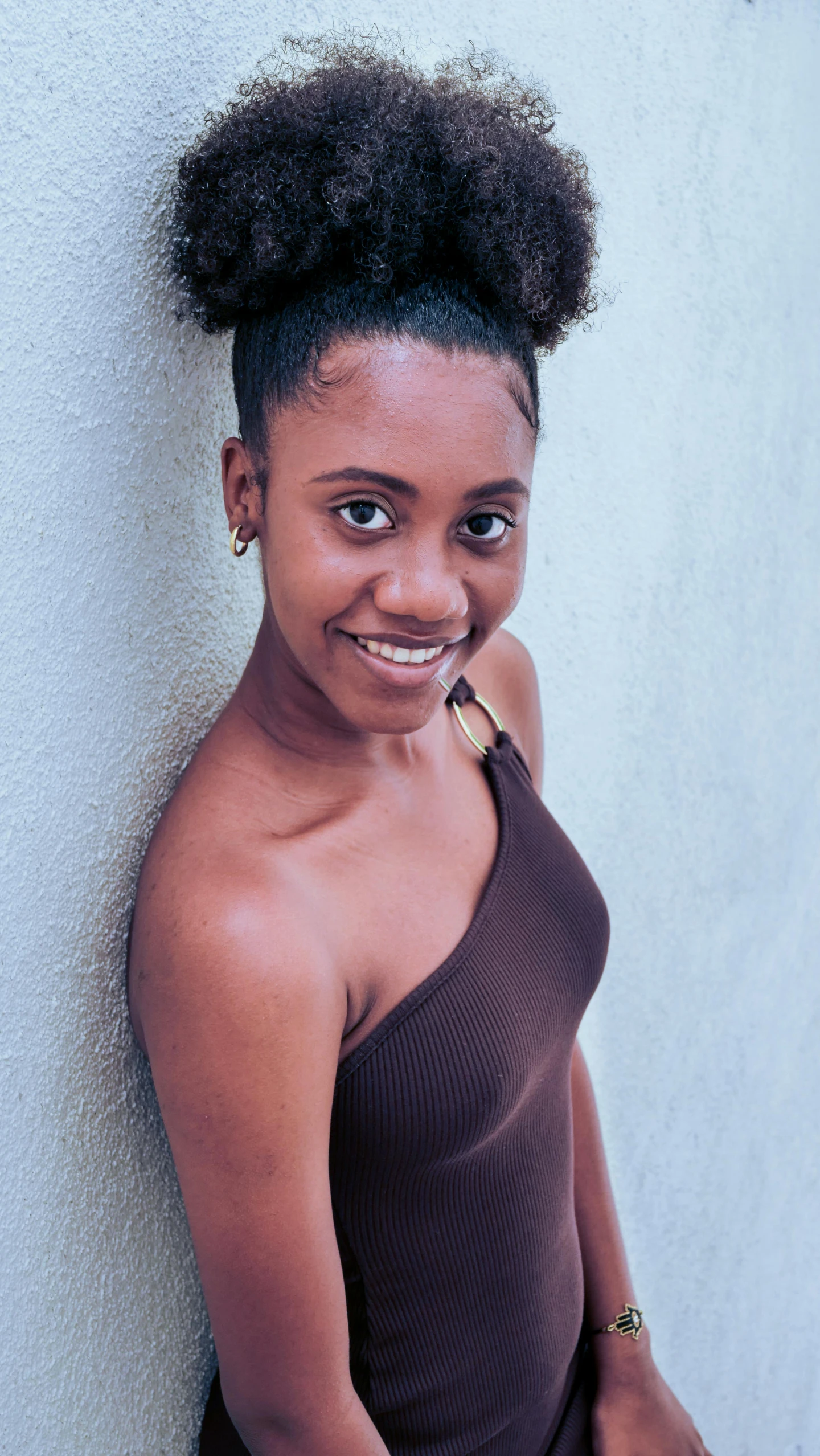 a woman standing next to a white wall