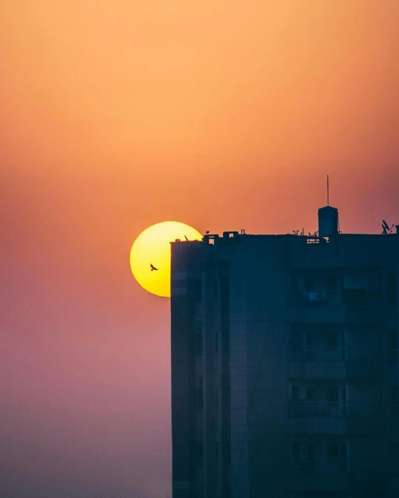 the sun is setting over the sky above an apartment building