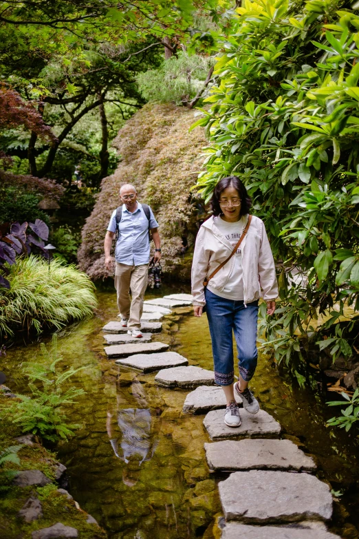 two people cross the stepping stones across the creek