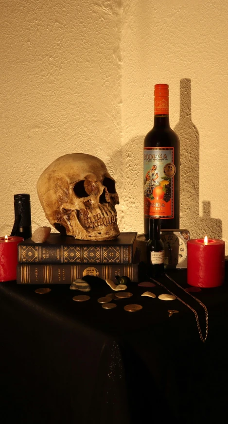 the remains of a human skull, candles, books and a bottle of liquor