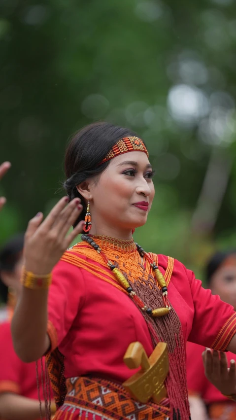 a woman is dressed in colorful clothing and holding her hands up