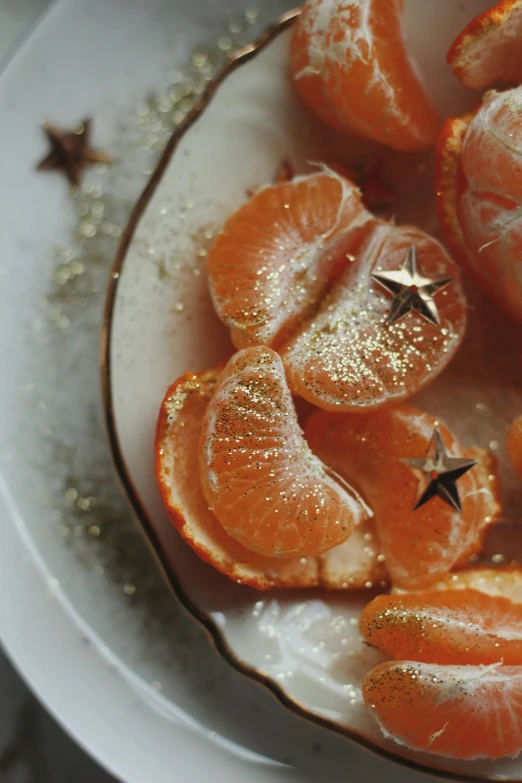 orange halves with glitter on them sit in a white bowl