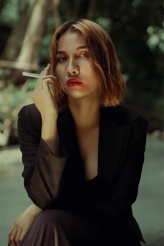 a woman sitting on the ground smoking a cigarette