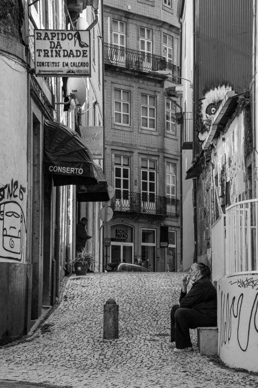 a man sits on a curb next to tall buildings