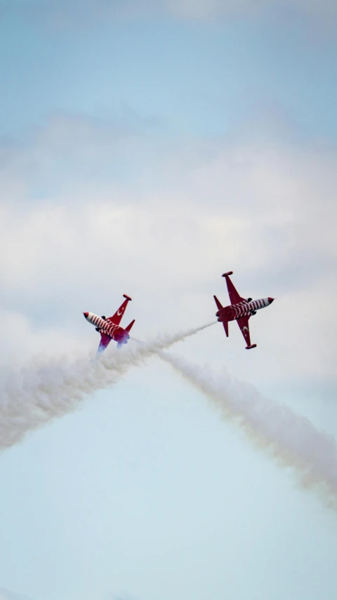 two jets in the air leaving a long trail of smoke behind them