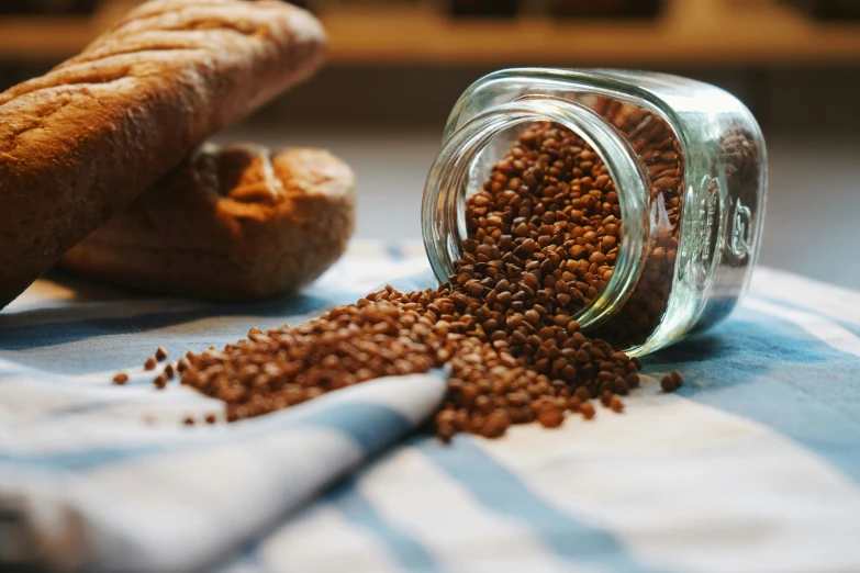 a glass jar full of mustard next to a loaf of bread