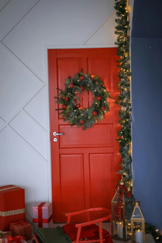 a red front door with a wreath and gifts around it