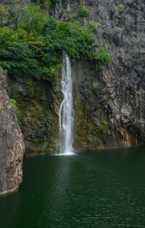 waterfall in body of water near steep cliff