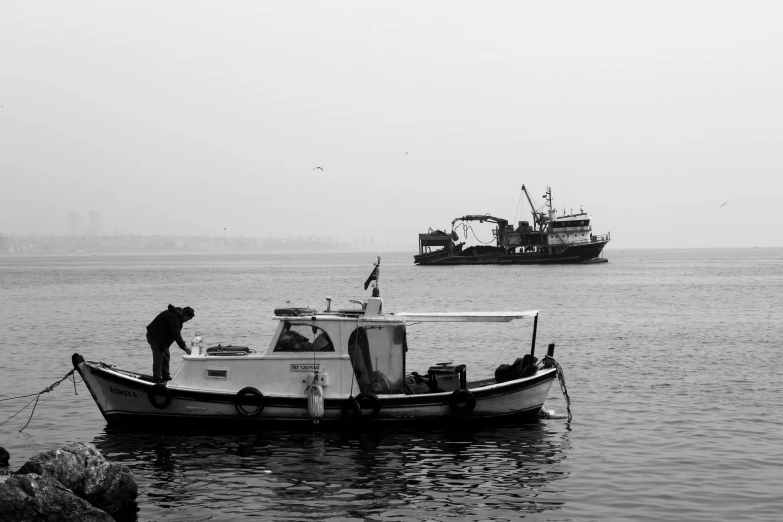 a black and white po of a boat in the ocean with a tugboat and an american flag hanging out