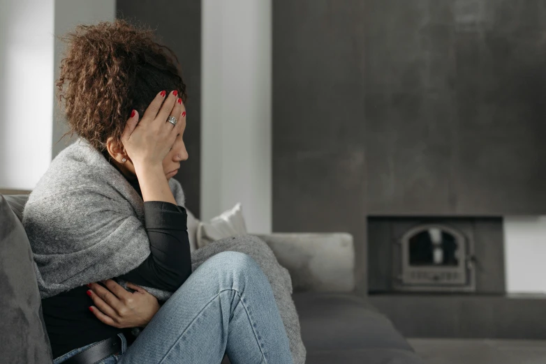 a woman sitting on a couch holding her head