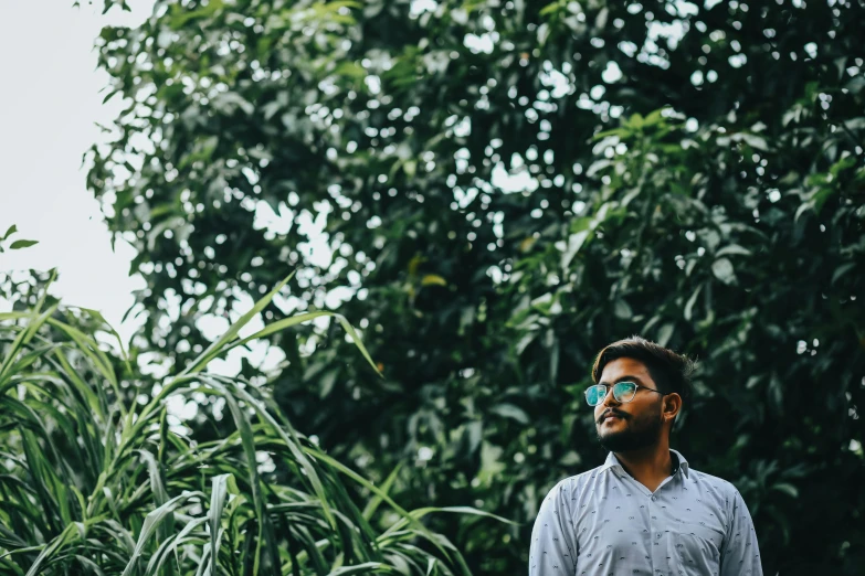 man wearing eye glasses in the woods looking away