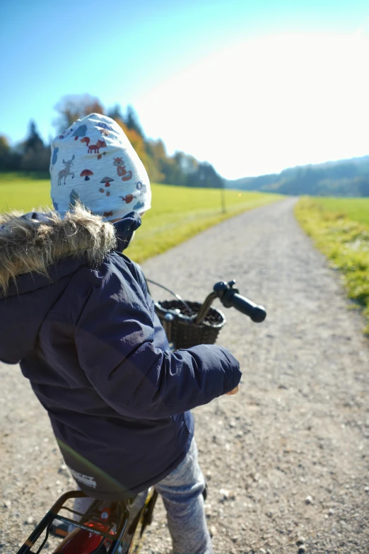 a young person riding on a bike down a dirt road