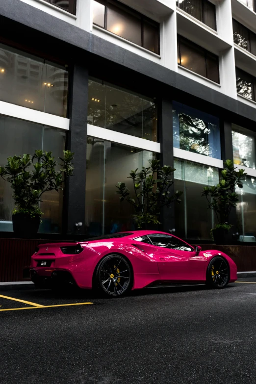 a pink sports car parked in front of a tall building