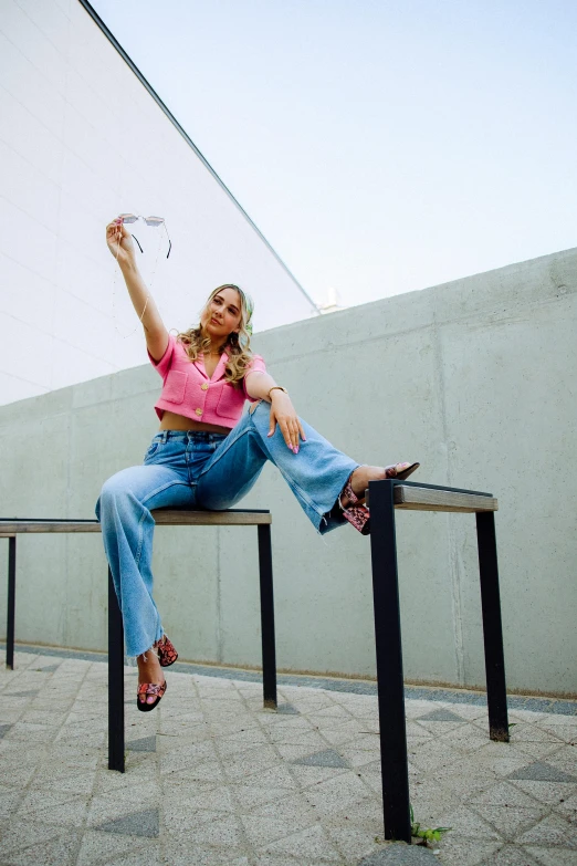 a woman sitting on a rail outside with her arms in the air