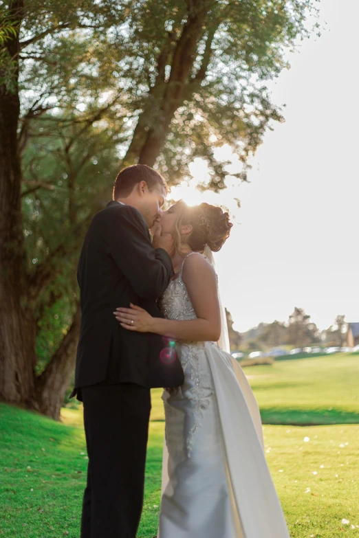 the bride and groom are standing under a tree