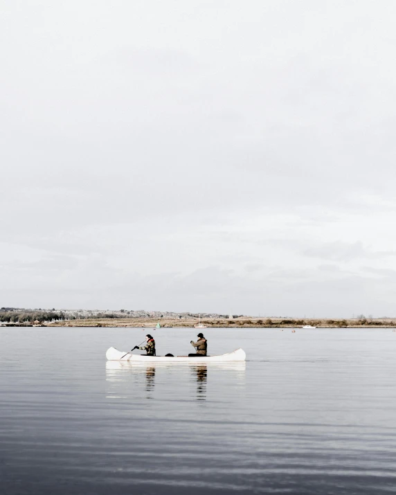 two people in a rowboat on a calm lake