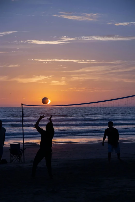 two people playing volleyball in the evening