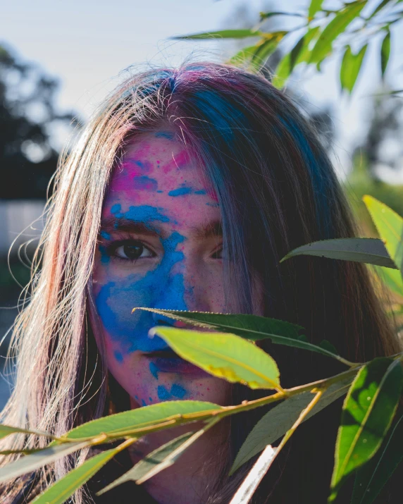 a woman's face covered in blue and purple holi