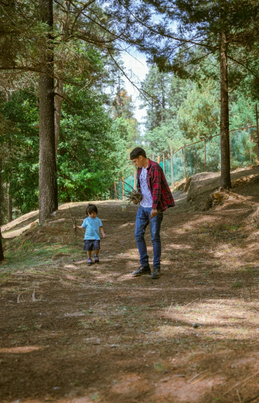 a man and a small boy walking together through a forest