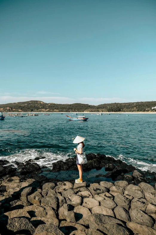 young woman on a rock by the water on a sunny day