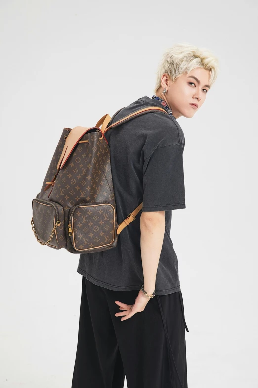 a young man with blonde hair carrying his louis vuittier bag