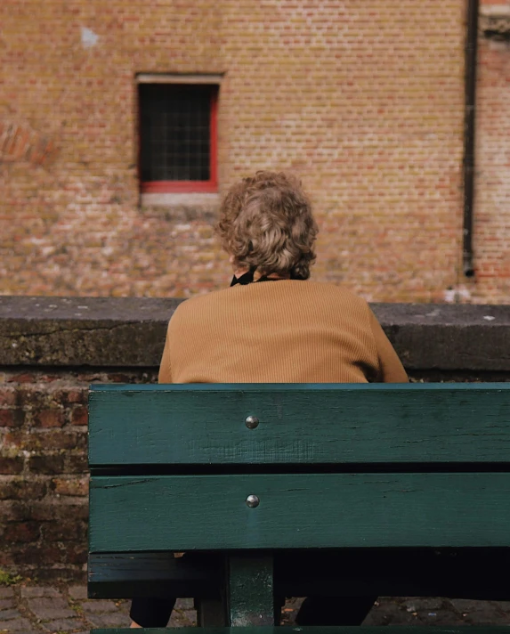 an elderly person sitting on a bench looking off into the distance