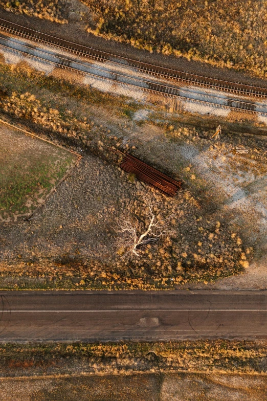 an aerial view of a road, trees and a dirt field