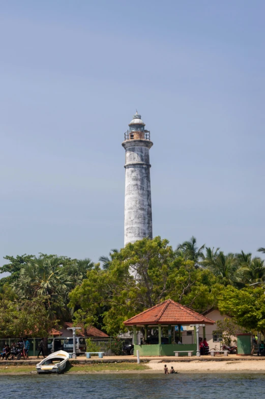 a boat is on the water in front of a large lighthouse